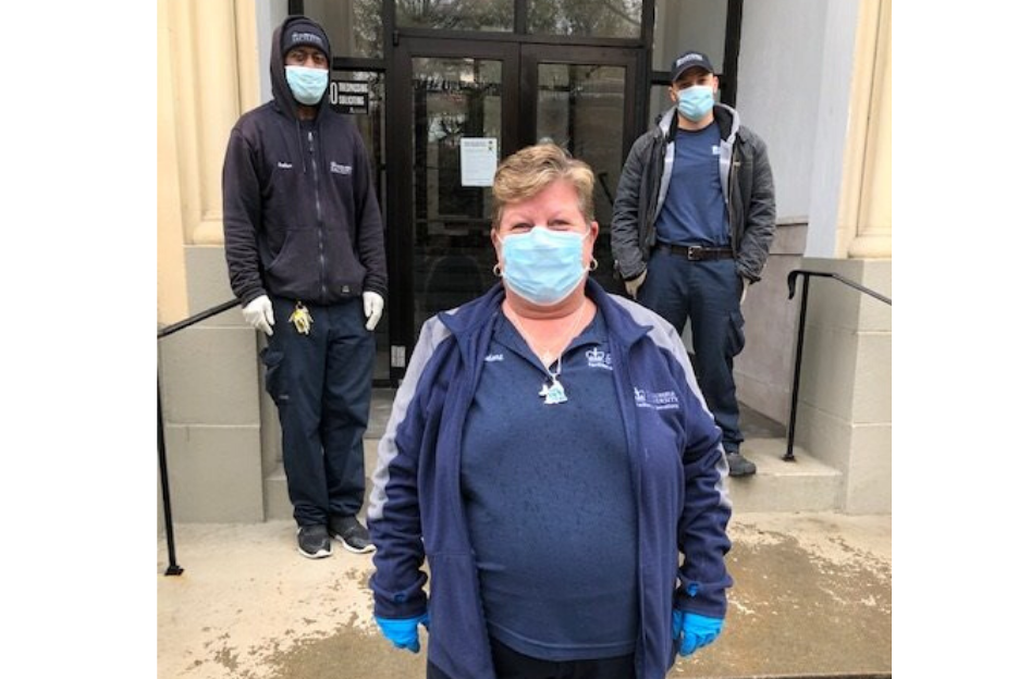 two men and one woman with Columbia branded jacket and polo with face masks in front of residential building