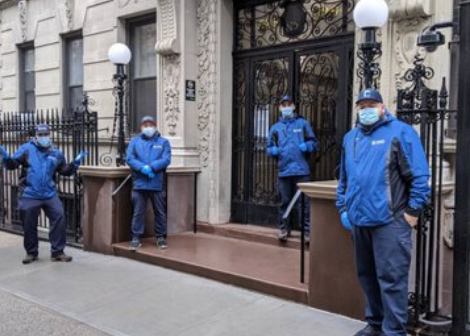 four men wearing face masks and Columbia branded in front of residential buidling