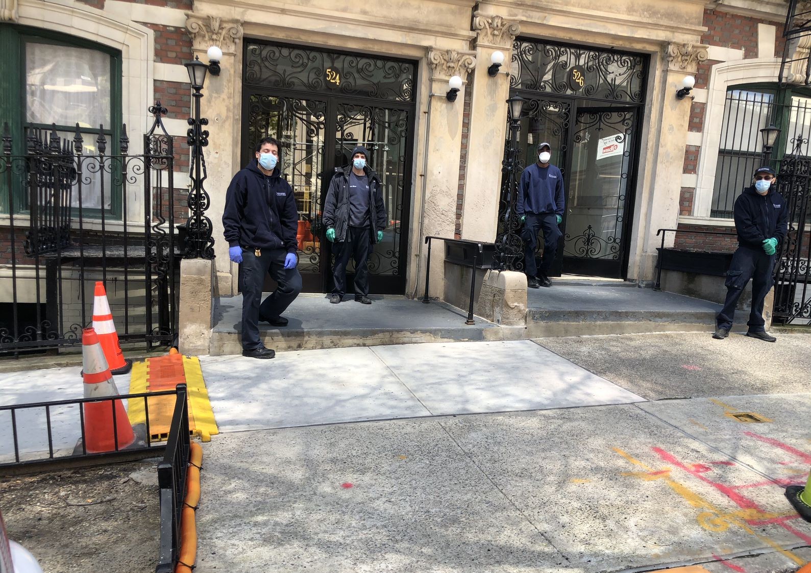 four residential staff members wearing face masks in front of residential building