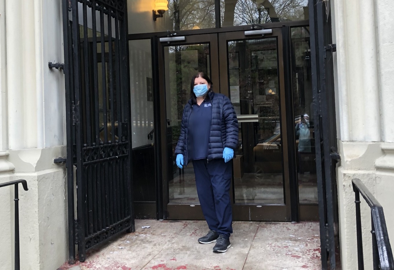 Residential staff wearing mask, standing in front of building