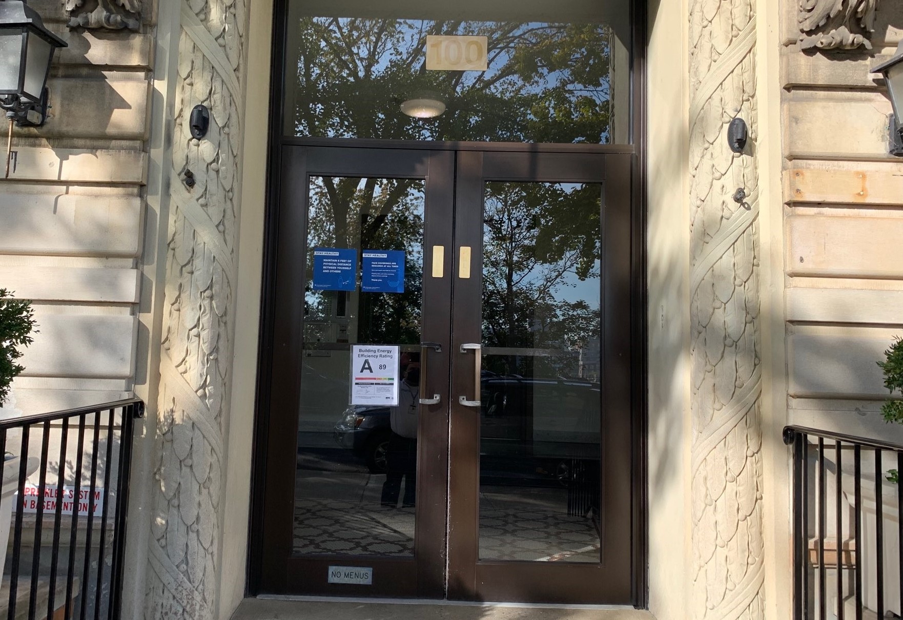 A residential building entrance that has an A energy efficency sign posted on the glass door.