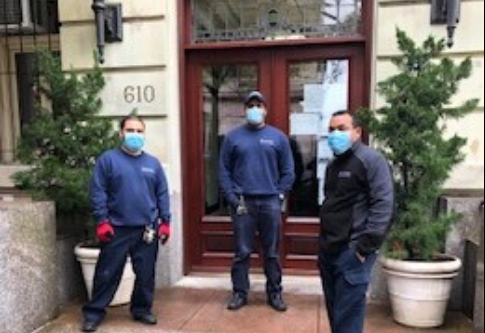 three men wearing face masks in front of residential building