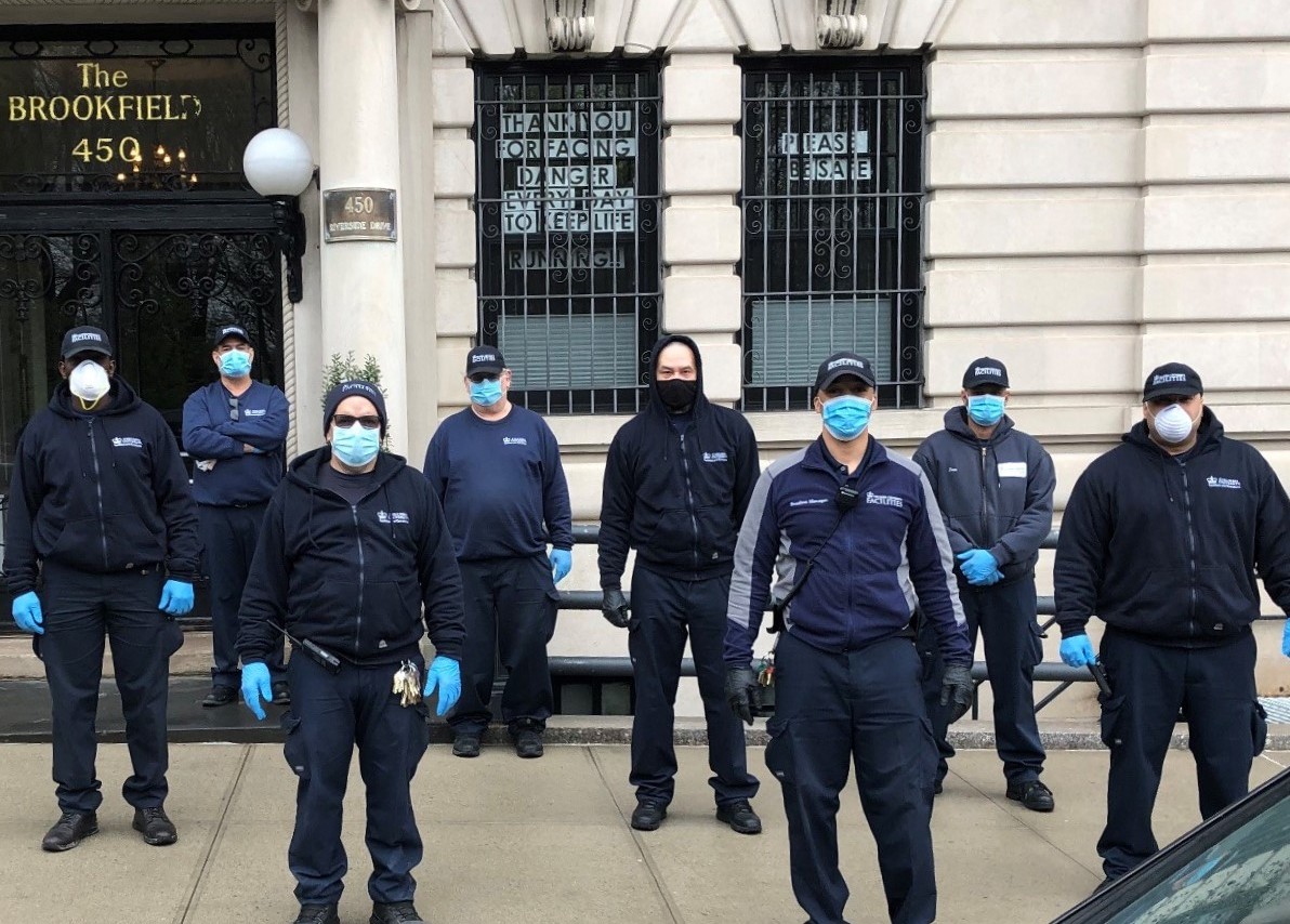 Eight residential staff members wearing masks, standing in front of a residential building