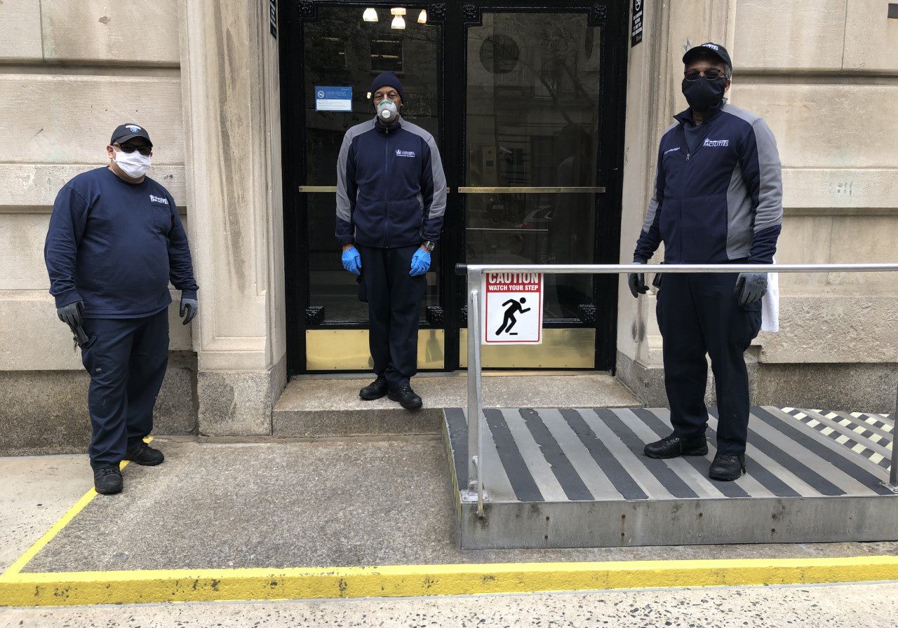 three residential staff members wearing face masks in front of residential building