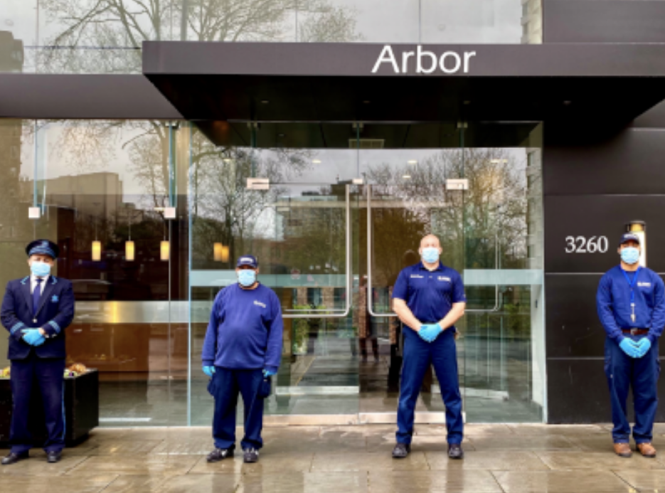 four residential staff members wearing face masks in front of residential building