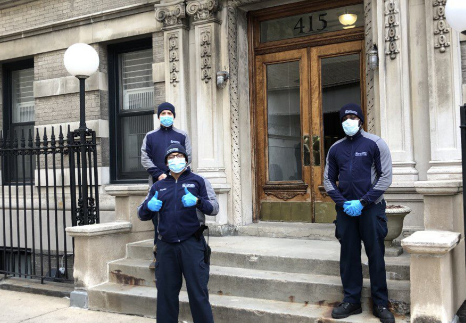 three men with face masks in front of residential buildings