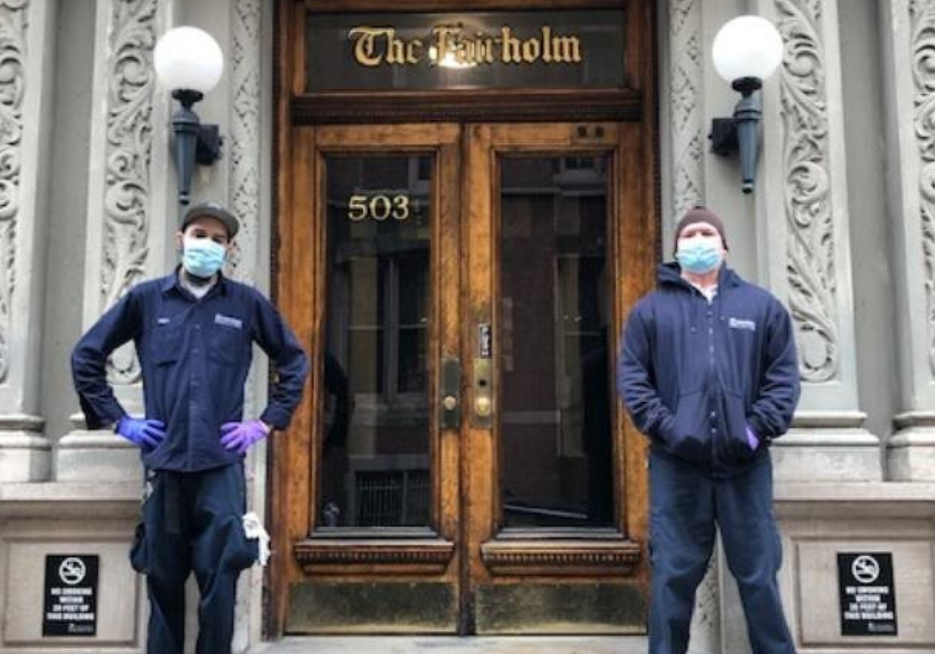 two men wearing face masks and Columbia branded jackets in front of residential building