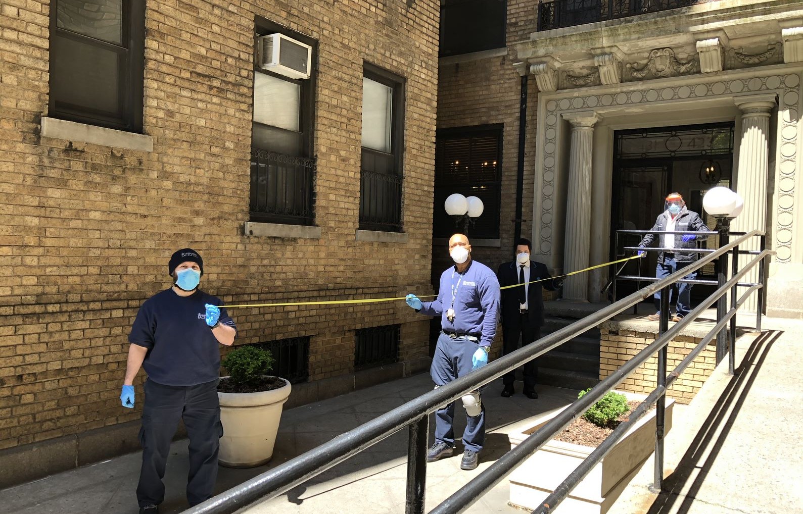 four residential associates wearing face masks in front of residential building