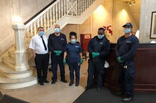 five residential associates, three men and one woman, wearing face masks inside residential building lobby