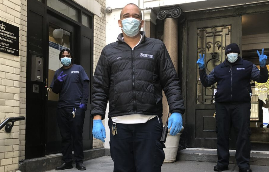 three residential associates wearing masks and Columbia branded jackets in front of residential building