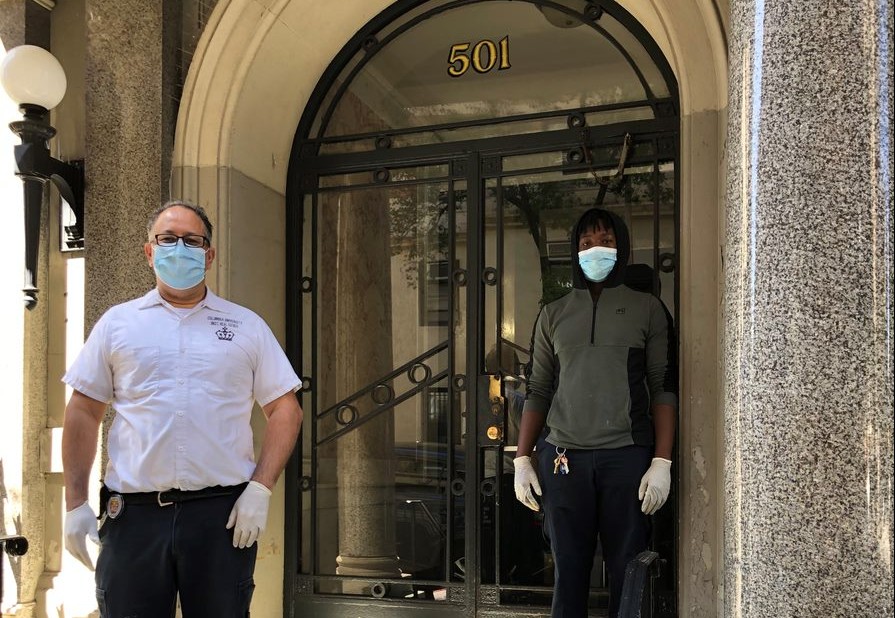 two men wearing face masks in front of residential building