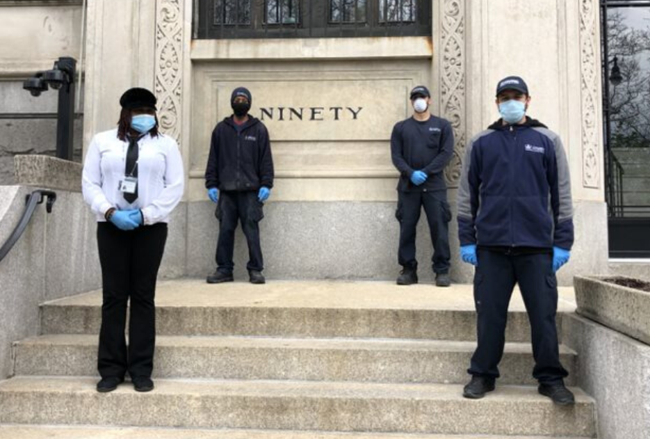 four residential staff members wearing face masks in front of residential building