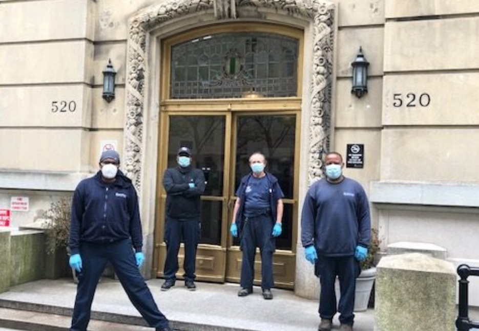 four men with face masks and Columbia gear in front of residential building