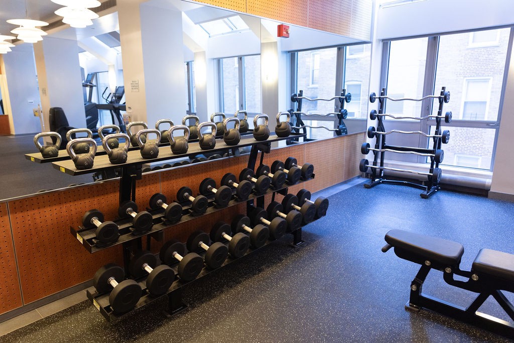 Photo of rows of barbells, dumbells and kettle bells in front of a mirror.