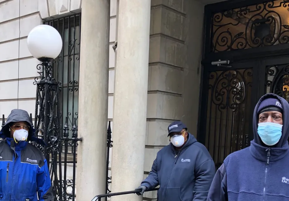 three residential associates with masks in front of residential buildings