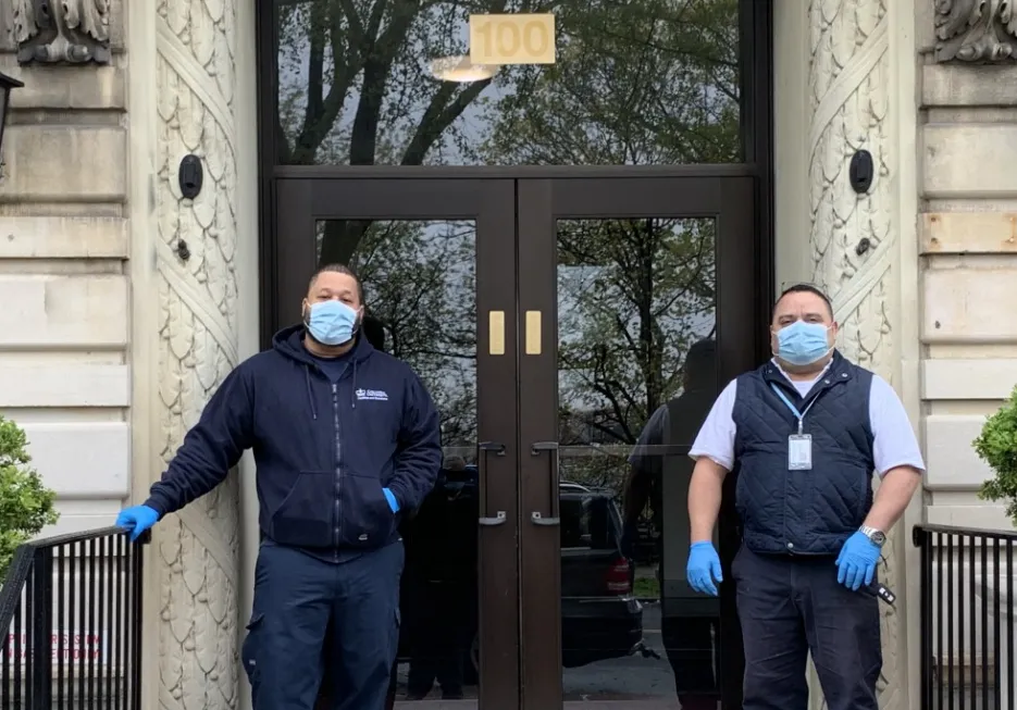 two men wearing face masks in front of residential building