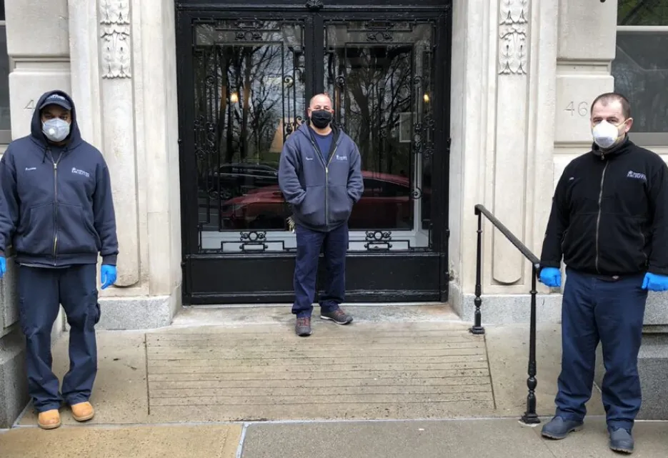 three men wearing masks in front of residential building