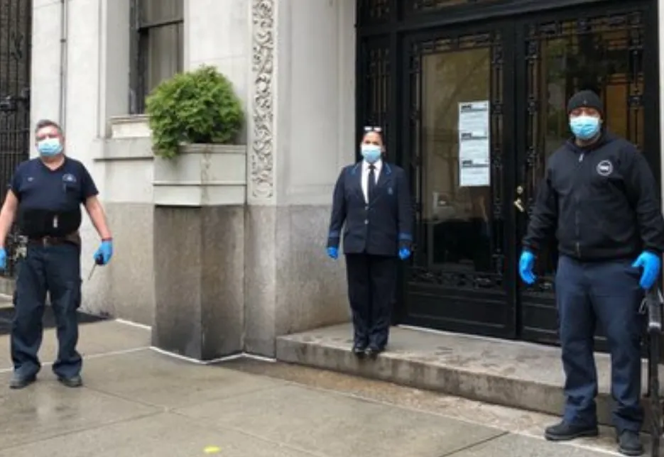 two men and one woman with face mask in front of residential building