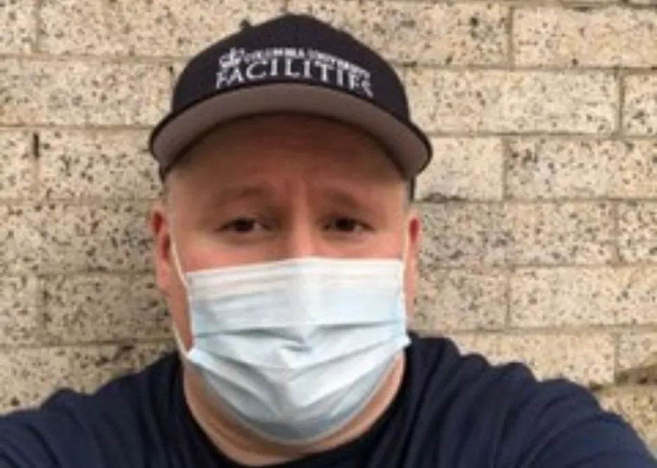man wearing face mask and Columbia Facilities branded hat