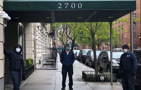 three men wearing face masks in front of residential building