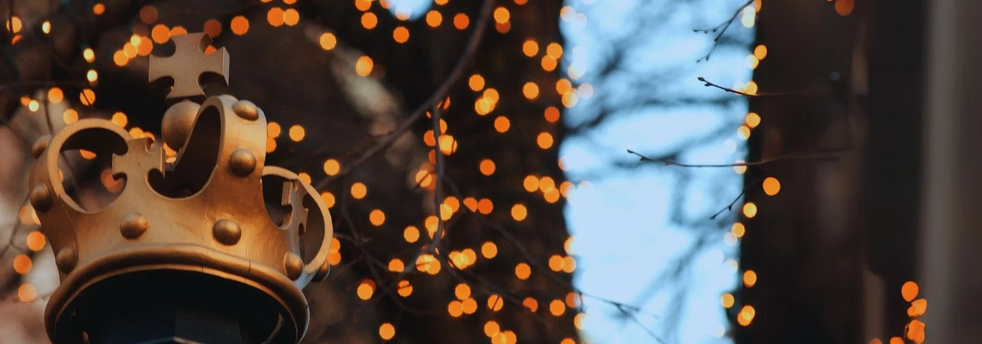 Photo of campus highlighting a bronze statue of the Columbia crown against twinkle lights.