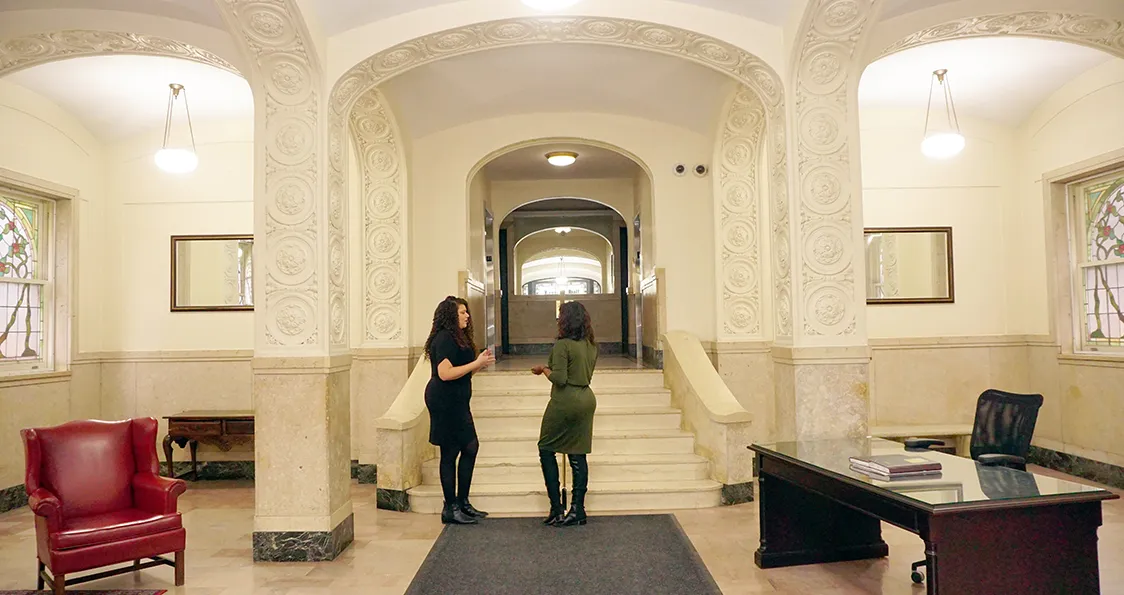 A view of the interior lobby at 424 430 W. 119th with two people speaking near the staircase